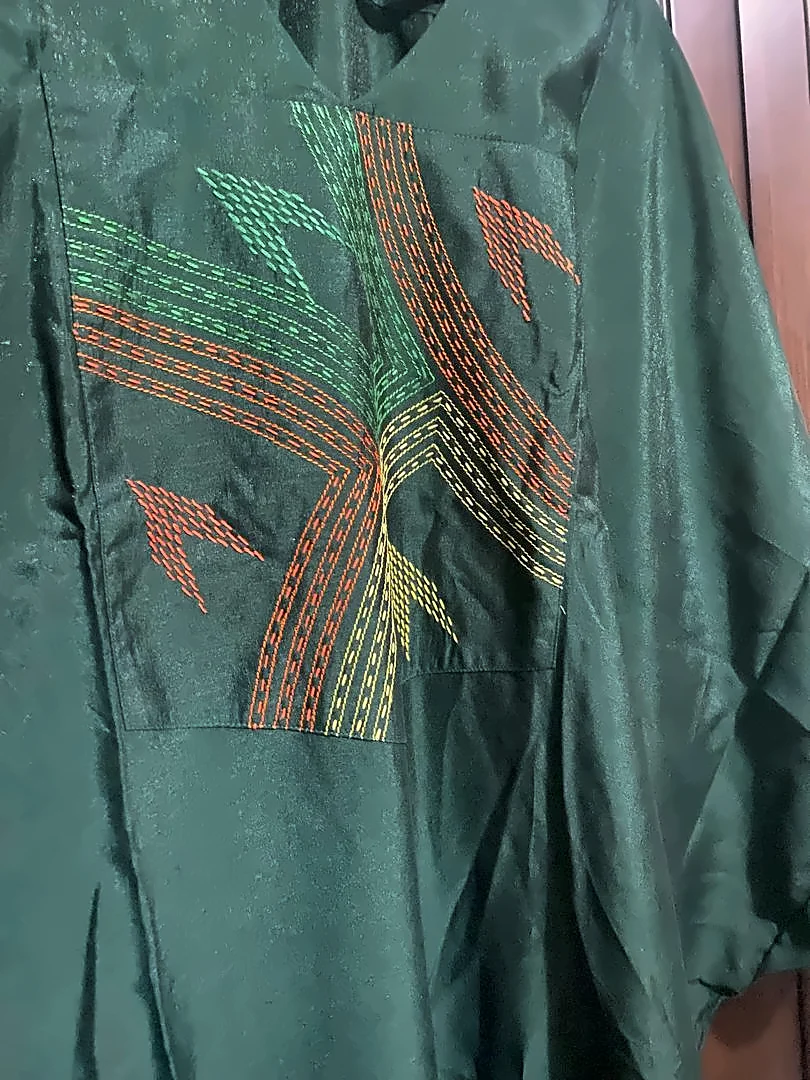 Tenue vert émeraude, plastron surpiqué de lignes vertes, orange et jaunes